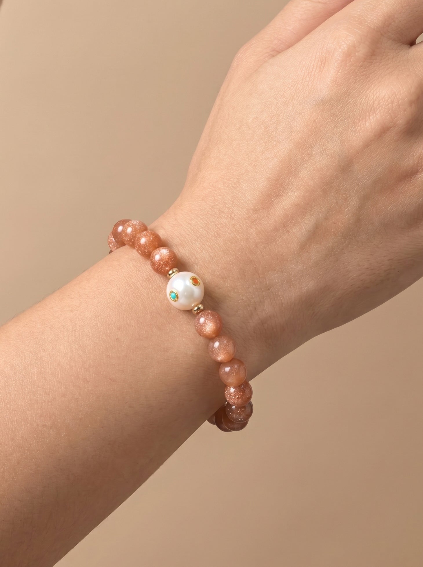 Sunstone and pearl bracelet worn on wrist